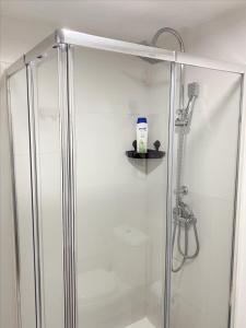 d'une douche avec une porte en verre et une bouteille sur une étagère. dans l'établissement Mima House Al, à Aveiro 51 autres photos