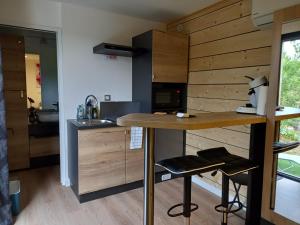 a kitchen with wooden walls and a counter with stools at "Plus belle l'Ardèche" Studio de jardin et piscine in Vinezac