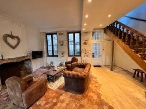una sala de estar con muebles de cuero y una escalera. en Maison dans quartier historique : La Grenouille en Avallon