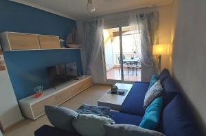 Atico Apartament Rose في مار ذي كريستال: غرفة معيشة مع أريكة زرقاء وتلفزيون