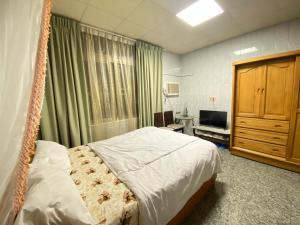 a bedroom with a hanging bed and a television at Enoya Homestay III in Linbian
