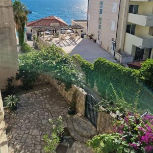 a stone walkway leading to a building with flowers at Apartments Rales in Sveti Stefan