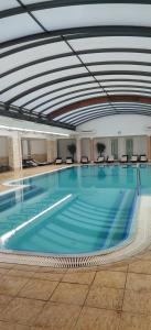 a large swimming pool with blue water in a building at Áron Apartman-Zalakaros in Zalakaros