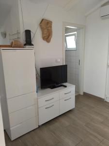 a living room with a television on a white cabinet at Apartman Barada in Slatine