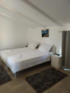 a bedroom with a large bed with white sheets and pillows at Apartman Barada in Slatine