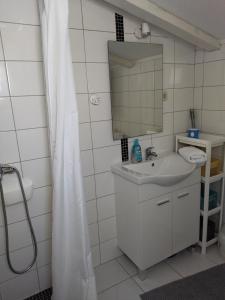 a white bathroom with a sink and a mirror at Apartman Barada in Slatine +12 photos