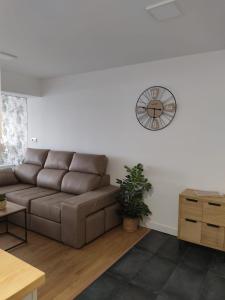 ein Wohnzimmer mit einem Sofa und einer Uhr an der Wand in der Unterkunft Apartamento pequeño, coqueto y céntrico. in Cedeira