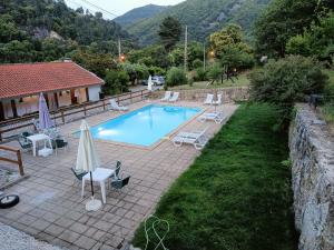 a swimming pool with chairs and umbrellas next to a house at Quinta de Leandres in Manteigas