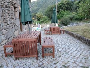 eine Gruppe von Bänken und Sonnenschirmen auf einer Terrasse in der Unterkunft Quinta de Leandres in Manteigas