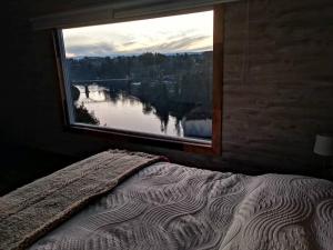 1 dormitorio con ventana y vistas al río en Altavista comodidad modernidad y seguridad, en Ranco