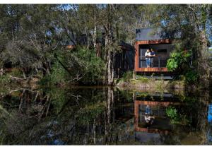 un hombre y una mujer parados en el balcón de una casa junto al agua en Discovery Parks - Byron Bay en Byron Bay