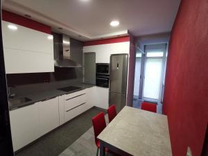 a kitchen with white cabinets and a table with red walls at Apartamento en San Sebastián con patio exterior in Añorga-Lugariz