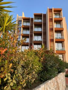 an apartment building with bushes in front of it at Hotel Olympia Touristic Village in Vlorë