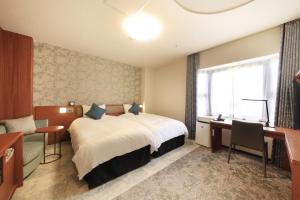 東京にあるリッチモンドホテル東京目白のベッド、デスク、窓が備わるホテルルームです。