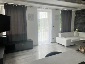 uma sala de estar com um sofá branco e uma televisão em R&H Ubytování u Českého Krumlova - Milenecký azyl - Penzion - Apartmán em Chvalšiny