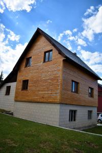 a large wooden building with windows on the side of it at Srna Chalet - Rooms in Žabljak