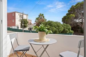 einen Tisch mit zwei Stühlen und eine Pflanze auf dem Balkon in der Unterkunft Ca Nostra Apartment in Cala en Porter