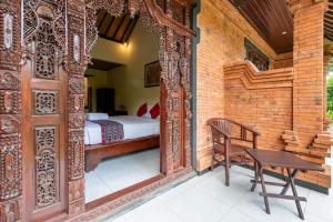 Schlafzimmer mit einem Bett und einer Holztür mit einer Bank in der Unterkunft Sanga Suites in Ubud
