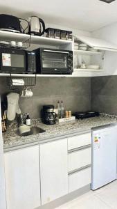 eine Küche mit weißen Schränken, einer Spüle und einer Mikrowelle in der Unterkunft Amazing Apartment in Palermo Hollywood! in Buenos Aires