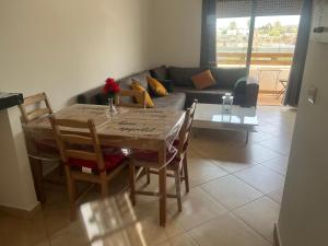a table and chairs in a living room with a couch at Appartement pied dans l eau à Residence Beralmar in Asilah