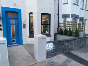 a house with a blue door and a stone wall at Coastline Retreats - Cloud9 Newly Renovated, Beautiful Ensuite Rooms Near Seafront in Town Centre, Netflix, SuperFast WiFi, Communal Kitchen in Bournemouth
