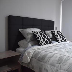 a bed with a black headboard and pillows on it at The Fox Departamentos in Santiago