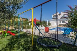a swing set in a yard with a pool at APARTMENTS ANA in Umljanović