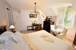 a bedroom with a bed and a table and chairs at Logis Hôtel De La Chapelle in Milon-la-Chapelle