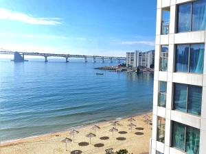 Blick auf einen Strand mit Sonnenschirmen und einer Brücke in der Unterkunft Holiday Apt Gwangan Beach in Busan