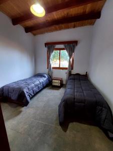 a bedroom with two beds and a window at Hostal killari in Cafayate