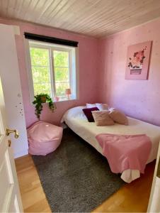 1 dormitorio con 2 camas, paredes de color rosa y ventana en Villa i Norrtälje en Norrtälje