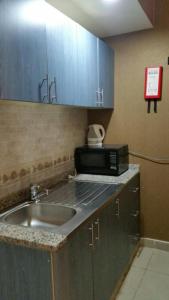 a kitchen with a sink and a microwave at Arabian Hotel Apartments in Ajman 