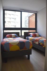Duas camas num quarto com duas janelas grandes em The Fox Departamentos em Santiago