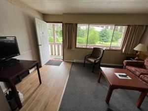 uma sala de estar com um sofá, uma mesa e uma televisão em Pioneer Inn by the River em Port Hardy