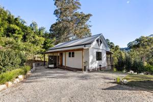 a small white house with a gravel driveway at Pool House Bellingen in Fernmount