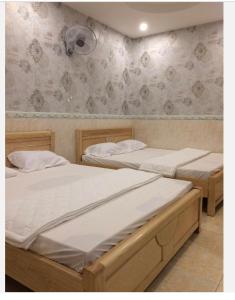 2 camas individuales en un dormitorio con pared en Nhà Nghỉ Nguyên Anh, en Long Hai