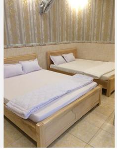 two beds sitting next to each other in a room at Nhà Nghỉ Nguyên Anh in Long Hai