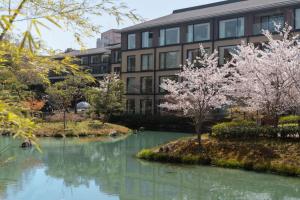Four Seasons Hotel Kyoto في كيوتو: بناء مع شجر اكورا في الماء أمامه