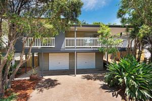 サンシャインビーチにあるDepper St Beautifully Renovated Beach Houseのガレージドア2つとバルコニー付きの家