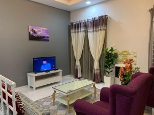 uma sala de estar com cadeiras roxas e uma televisão em Mok Moon Homestay Nearby Beach Pantai Kelulut - Marang em Marang