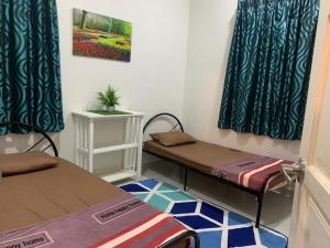 um pequeno quarto com duas camas e uma mesa em Mok Moon Homestay Nearby Beach Pantai Kelulut - Marang em Marang
