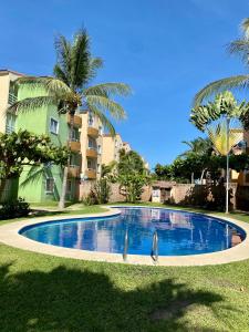 una piscina frente a un edificio con palmeras en Departamento planta baja en Acapulco Diamante, en Acapulco