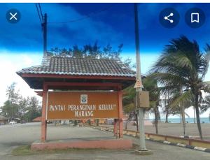 um sinal em frente a uma praia com um edifício em Mok Moon Homestay Nearby Beach Pantai Kelulut - Marang em Marang