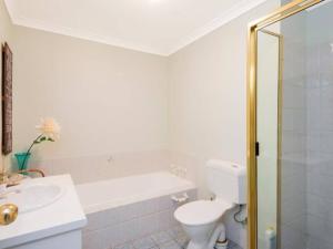 a white bathroom with a toilet and a sink at Adorable-secure 3 bedroom holiday home with Pool around the corner from The Miners Rest. in Kalgoorlie