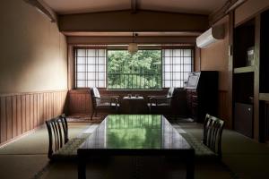 Zimmer mit einem Tisch, Stühlen und einem Fenster in der Unterkunft Fumoto Ryokan in Minamioguni