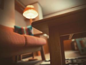 a room with a table and a lamp and a chair at Okushiga Lodge Yama no Manimani in Yamanouchi