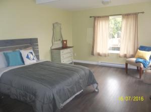 a bedroom with a bed and a chair and a mirror at Cottage Jasmine on the Shediac Bay with hot tub in Shediac