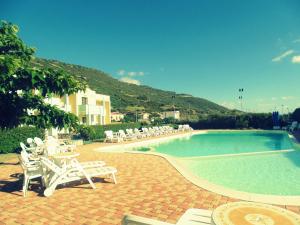 a pool with white chairs and a bunch of tables and chairs at Hotel Isola Rossa in Bosa
