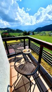 een patio met 2 stoelen en een tafel op een balkon bij Panorama adult only in Fundata