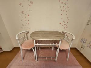 a table and chairs in a room with a wall at Takaraboshi room 301 Sannomiya 10 min in Kobe